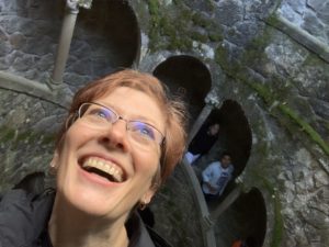 Blogger Mystique Macomber smiling while leaning back to look at light above at initiation well at Quinta de Regaleira in Sintra