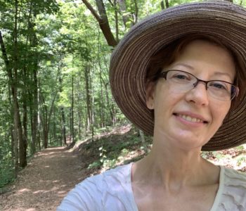 Blogger Mystique Macomber in a hat on a hiking trail in Tennessee