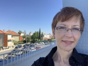 Blogger Mystique Macomber on balcony with Lisbon houses and street in background