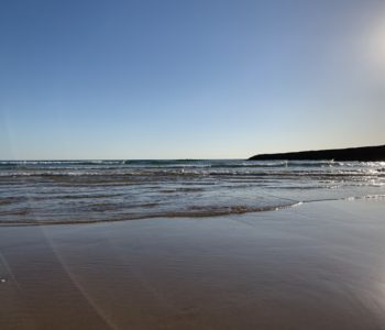 Ocean, sandy beach, sun in the blue sky