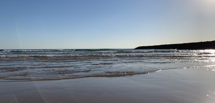 Ocean, sandy beach, sun in the blue sky