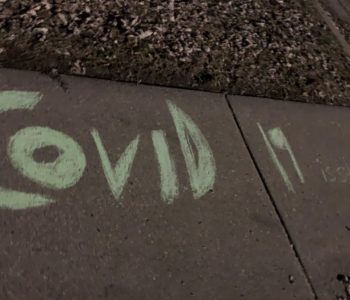 "COVID-19 is stupid" spelled in chalk on a sidewalk.